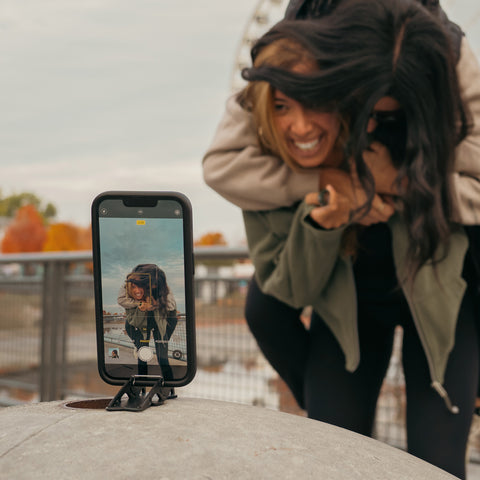 A tripod holding a phone that take a picture of two girls