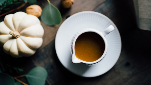 Bowl of gravy made with FOND bone broth sitting next to a small white pumpkin