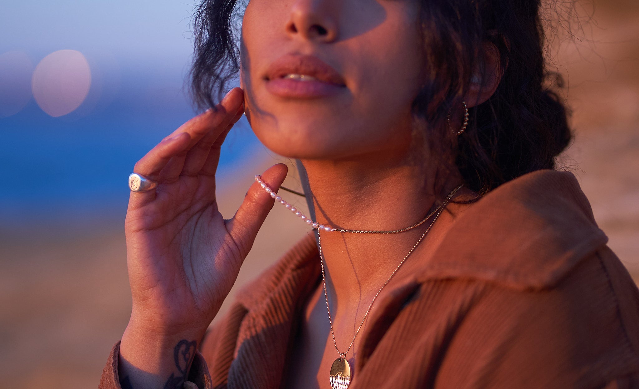 a woman wearing two necklaces and holding them up