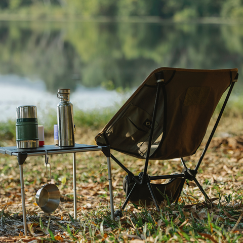 a single camping chair beside a table with two Thermos'