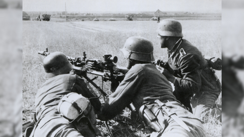 black and white shot of three wartime soldier aiming a gun across a field 