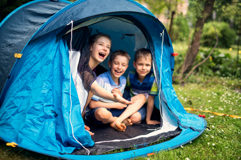 Boys laugh inside tent and feel for rain outside