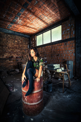 Female with war paint and camouflage outfit sitting in warehouse