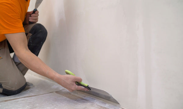 Skim coating wall with drywall knife