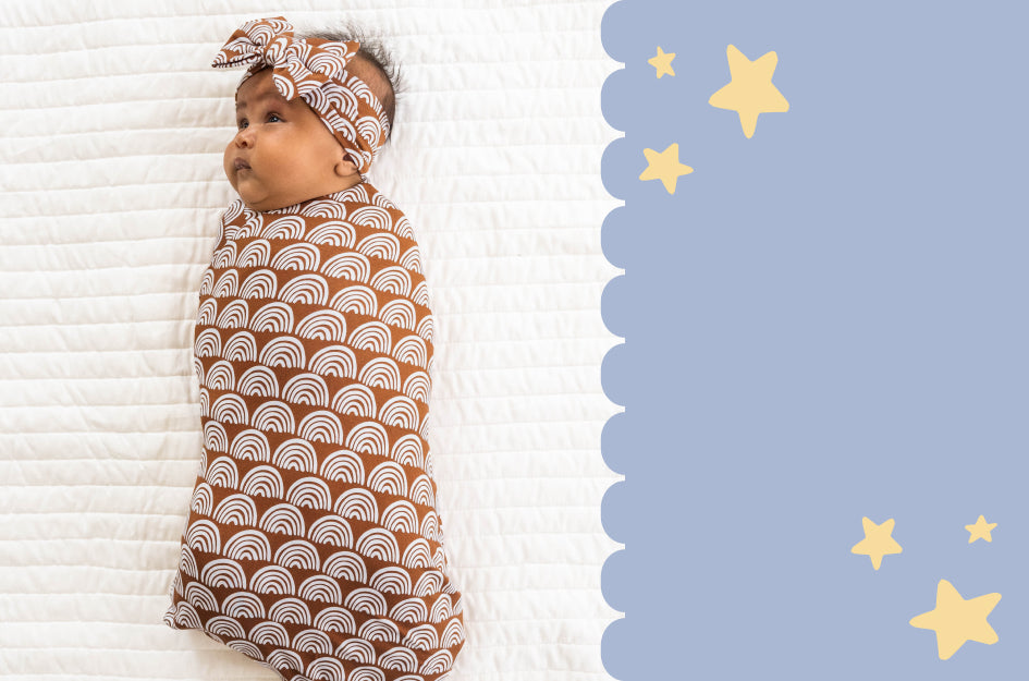 Image of an infant swaddled in a Rust Rainbows Swaddle and Luxe Bow Headband Set