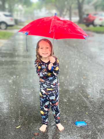 child in navy jurassic jungle pajamas in the rain