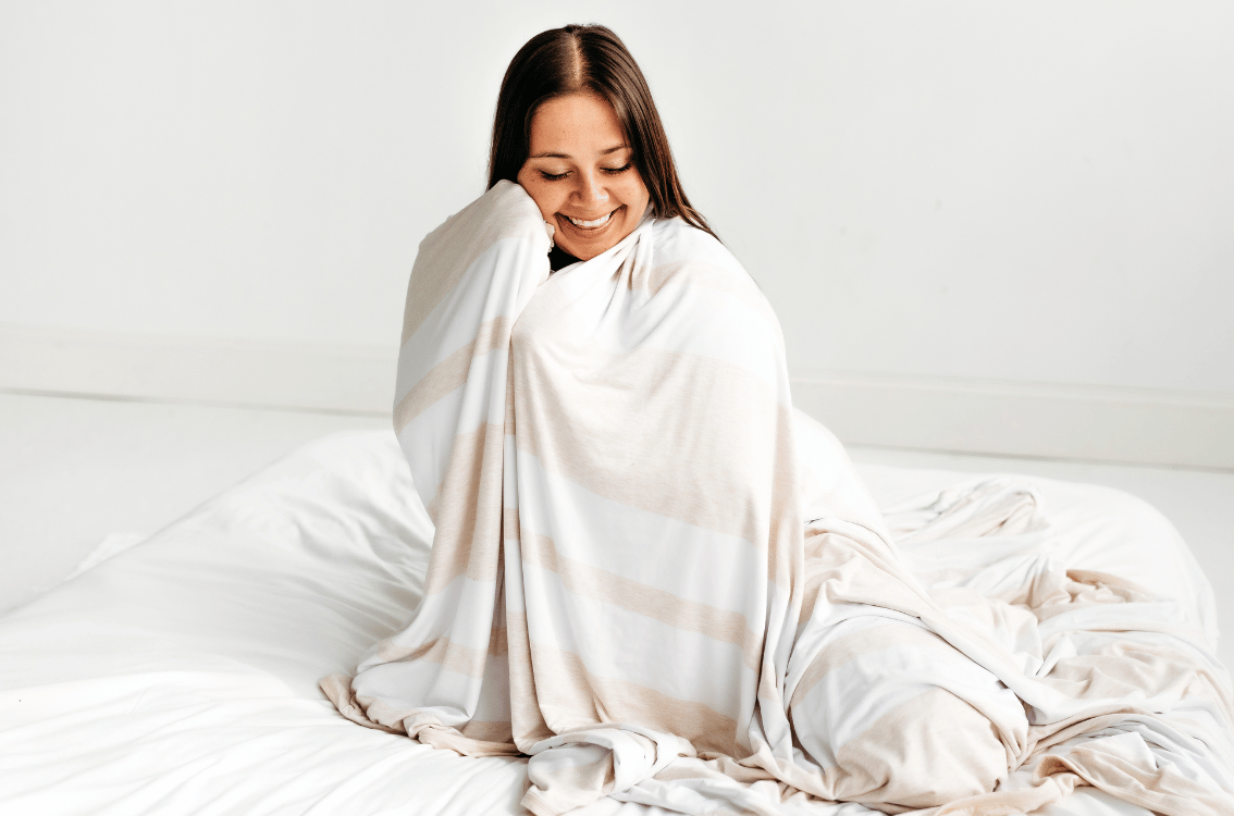 Woman cuddling with Heather Oatmeal Striped Oversized Cloud Blanket against her face.