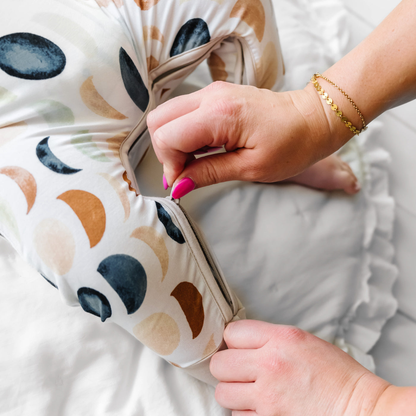 Close up image of a child wearing a Luna Neutral crescent zippy. Their mother is demonstrating the zippered leg