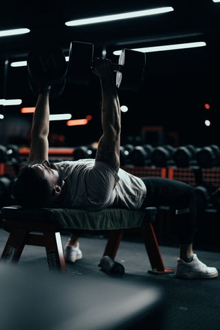 homme faisant un développé haltère sur un banc de musculation