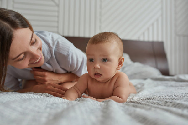 mom laying with baby on the bed doing tummy time