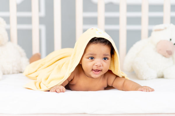 Baby doing tummy time with yellow towel covering them and resting on their head, clear from their face.