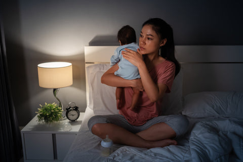 Mom burping baby late at night in dimly lit room