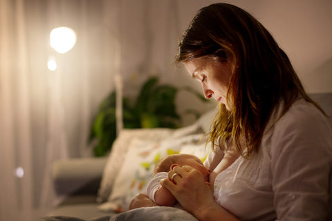 Woman feeding her baby in a dimly lit room
