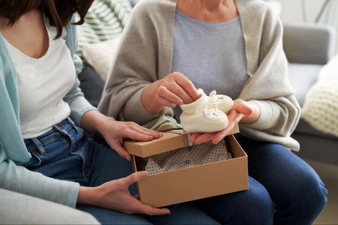 woman opening a gift of baby shoes