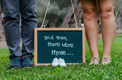 baby pregnancy announcement with feet and sign