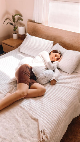 woman laying on a bed with pregnancy pillow