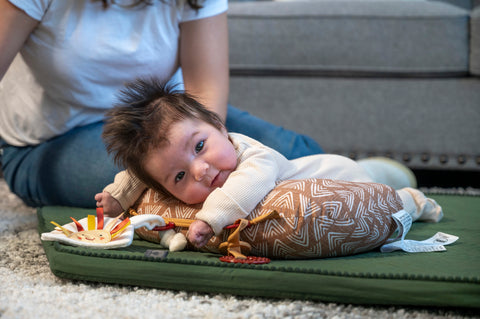 Baby playing with tummy time pillow while parent supervises