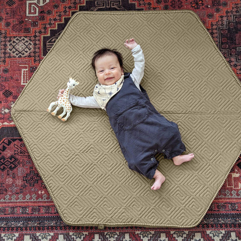 baby laying on a playmat with a toy