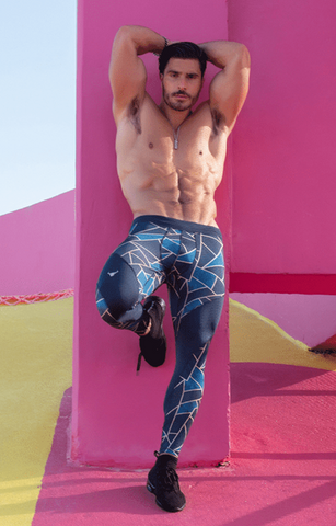 muscular male wearing geometric meggings and leaning against a pink building