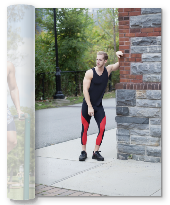 man in a black tank top and red & black leggings leaning up against a stone wall