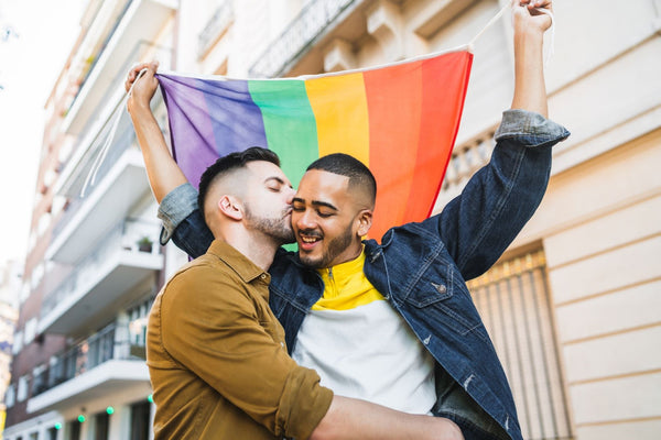 Man kissing man holding a pride flag