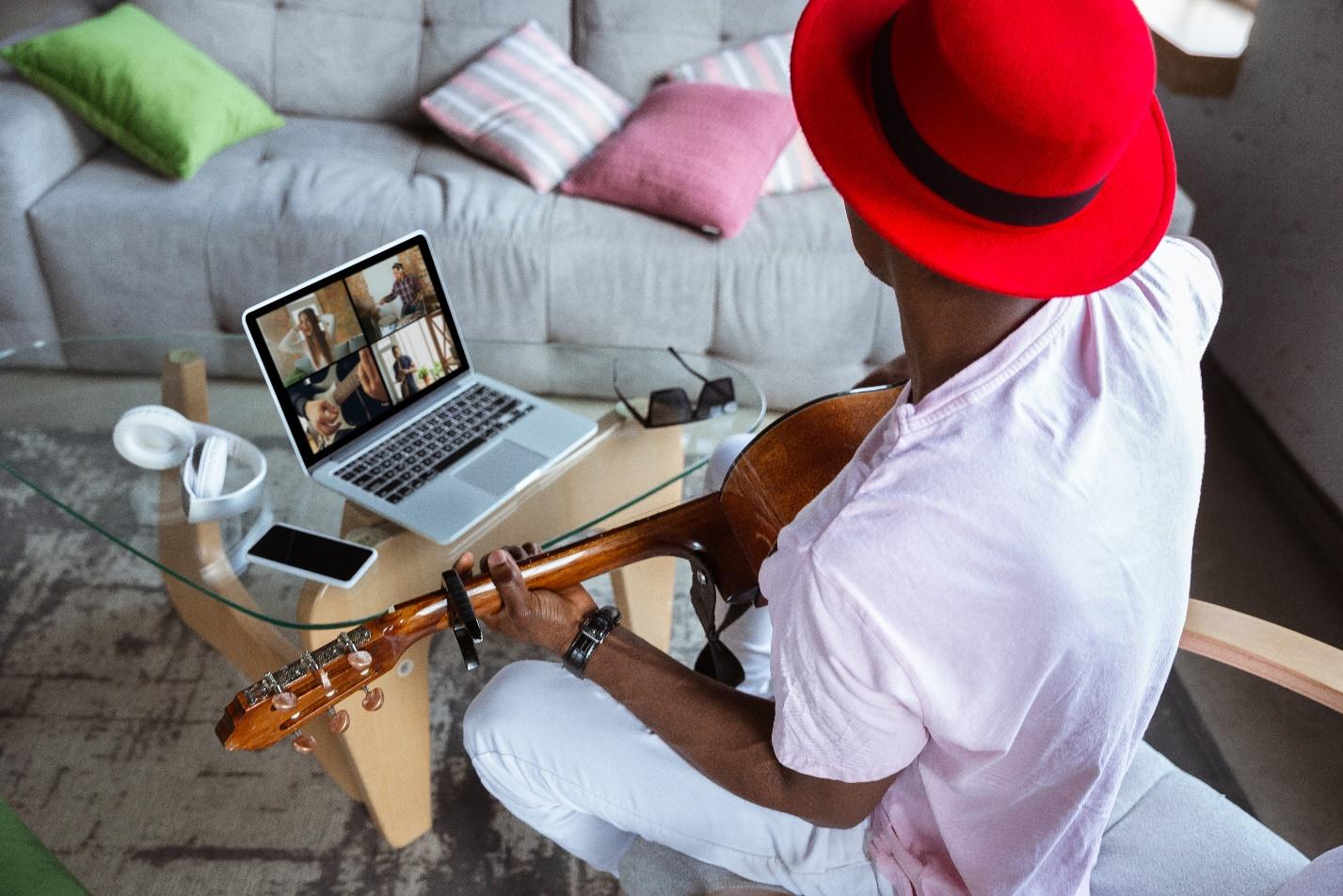 African-american musician playing guitar during online concert at home