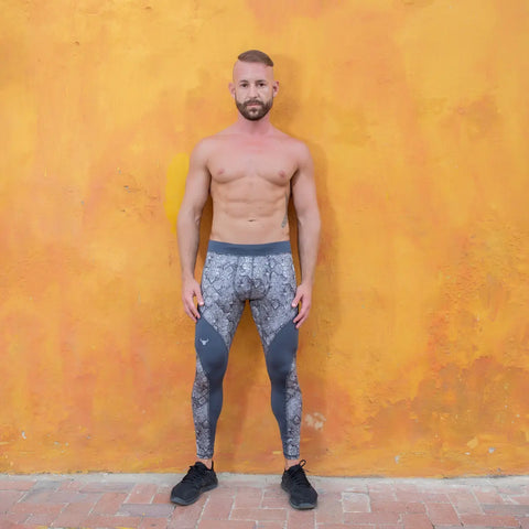 Running pants for men in stone-textured gray design worn by a fit model against an orange wall.