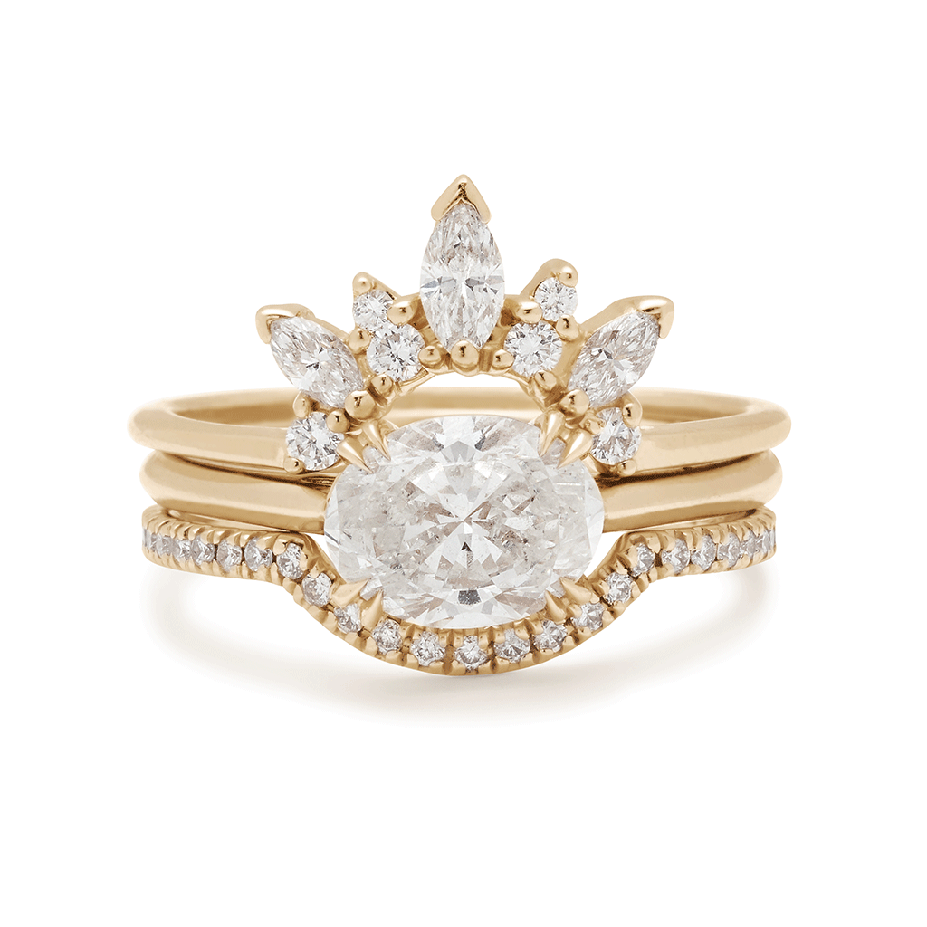 An east/west solitaire ring with a brilliant cut white diamond stone set in yellow gold and inbetween a marquise diamond band and scalloped white diamond band.