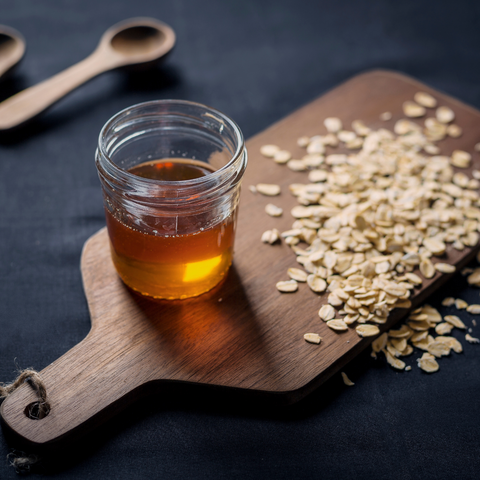 wooden cutting board with a jar of honey and rolled oats on it