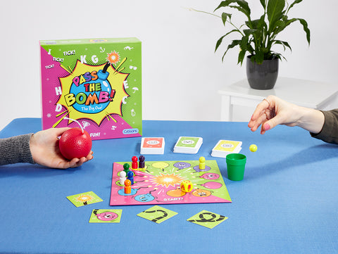 Two people playing Pass the Bomb The Big One on a blue table.