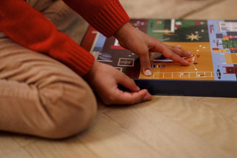 Child opening up a traditional chocolate advent calendar on hardwood floor.