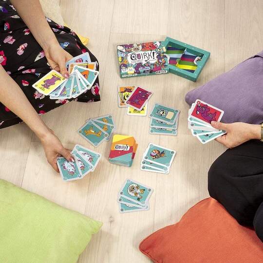 Children playing the Quirk family card game on the floor with cushions.