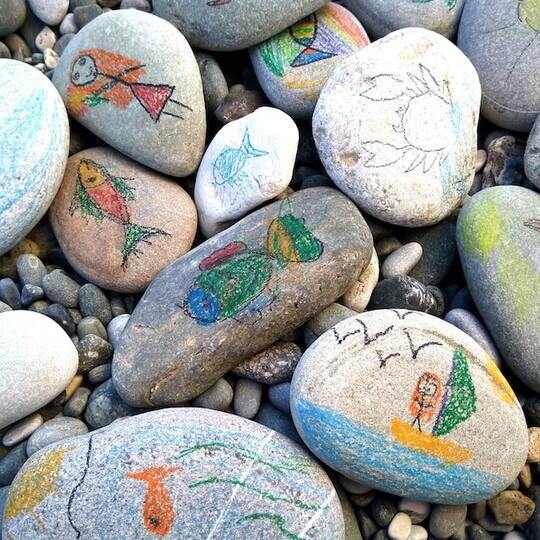 Children drawings on rocks and pebbles at the beach. 