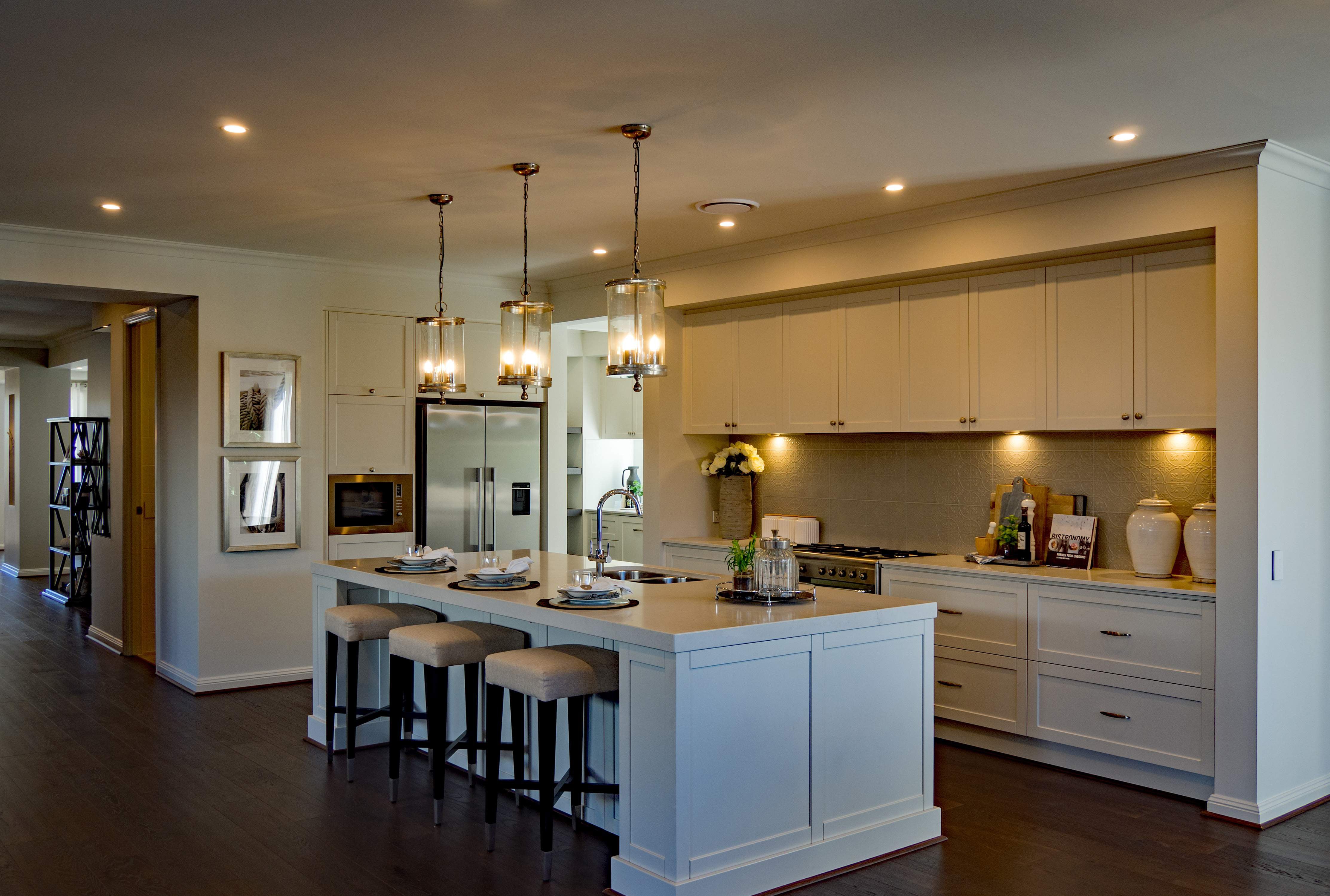 An elegant kitchen design with warm white downlights and glass pendant lights.