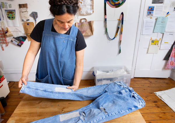 Celia Pym handling a pair of mended jeans in her studio