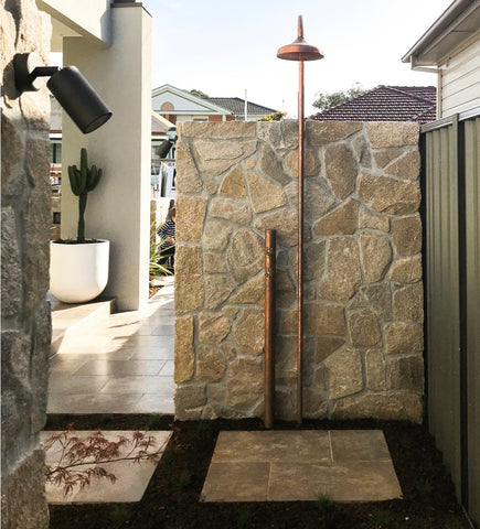freestanding shower in front of stone wall