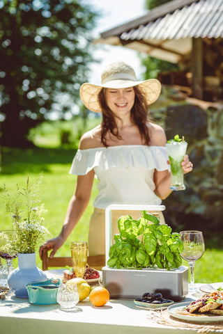 Woman with a smart herb garden in the summer sun.