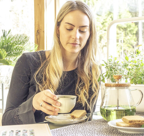 Woman drinking tea beside a window and a Click and Grow smart garden 9.