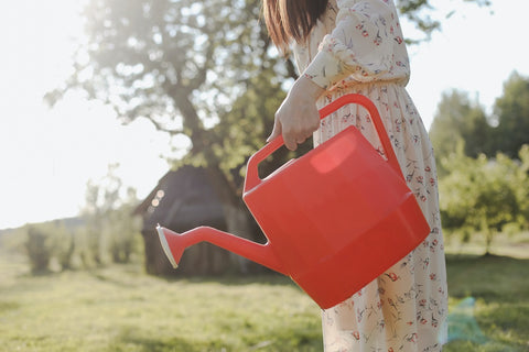Woman holding a red watering can.