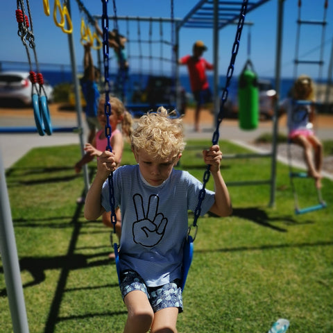 Little boy using the swing set with monkey bars