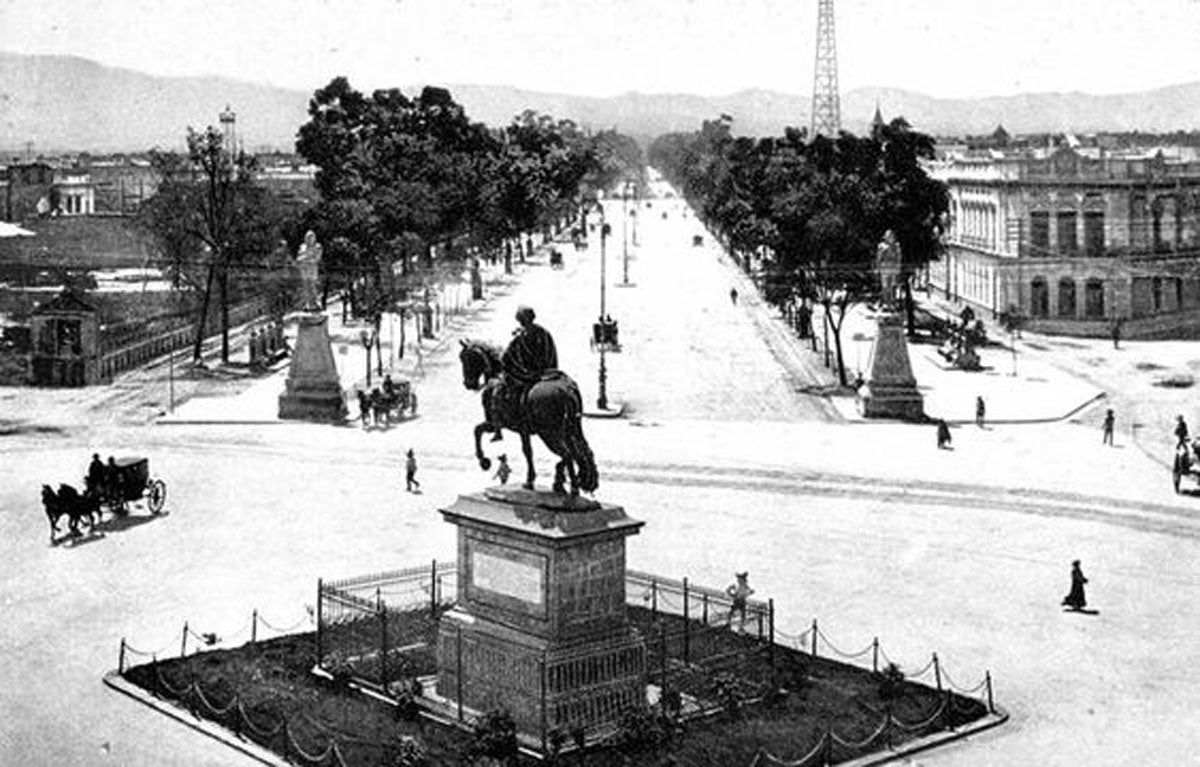 Esta foto es un poco posterior a 1900, donde se aprecia el punto de inicio original de Paseo de la Reforma, adornado con la estatua ecuestre de Carlos IV, actualmente en la explanada del MUNAL y las dos estatuas conocidas como los Indios Verdes (Izcóatl y Ahuízotl).