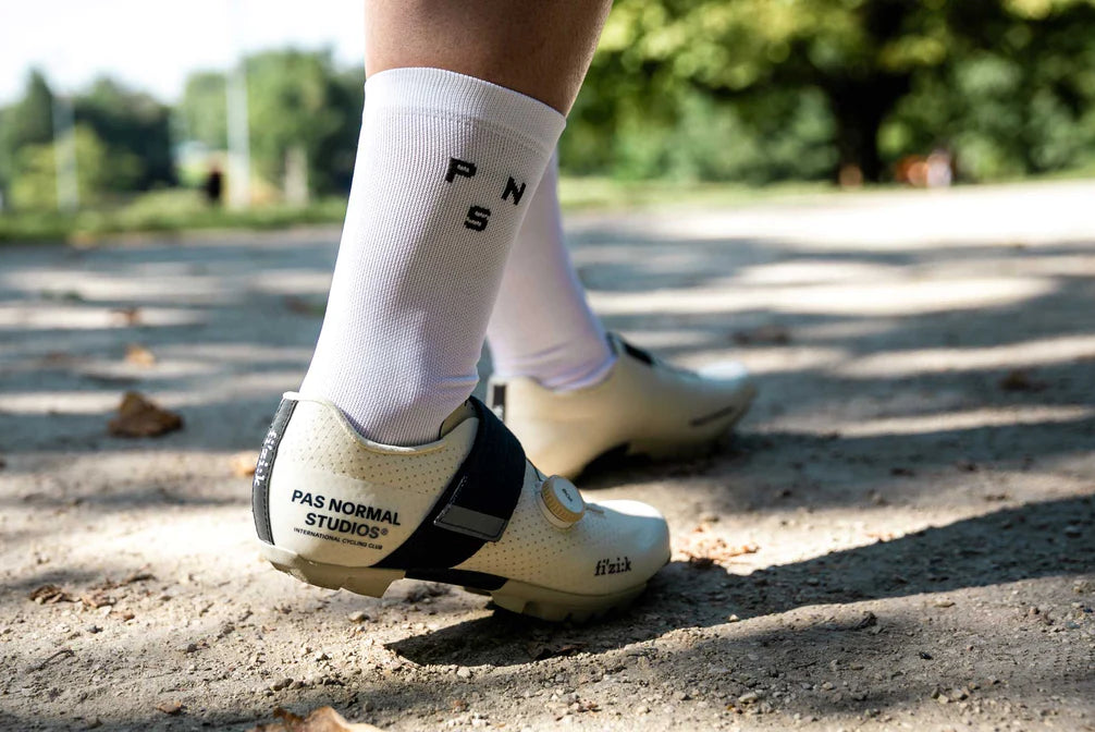 A cyclist walking in white cycling shoes