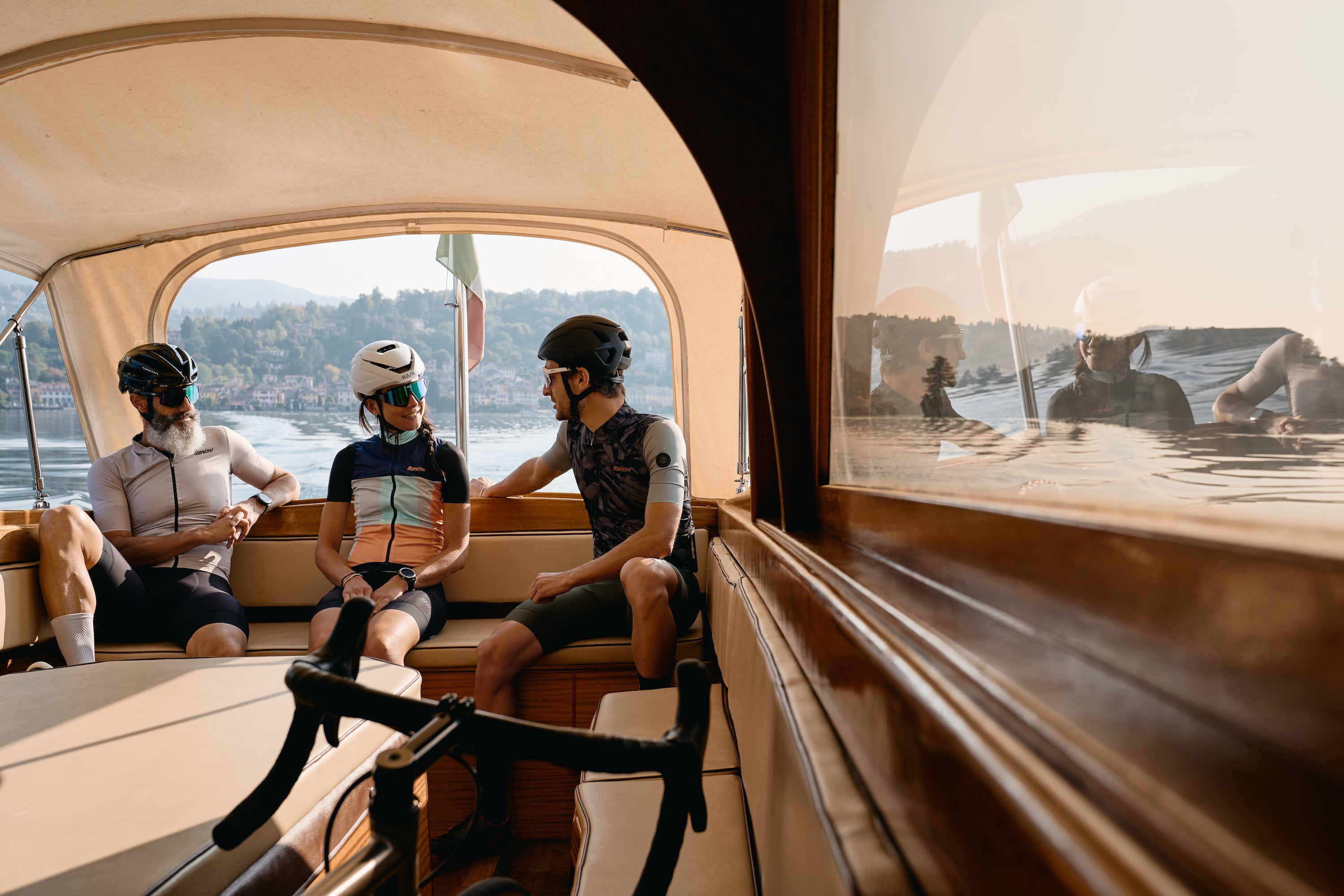 Three people in cycling kit on a boat
