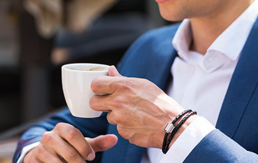 Man in suit with cremation bracelet and coffee cup