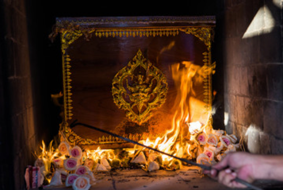 Person lighting incense at the urn site of someone