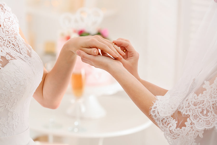 Close up of hands of lesbian wedding couple exchanging rings.