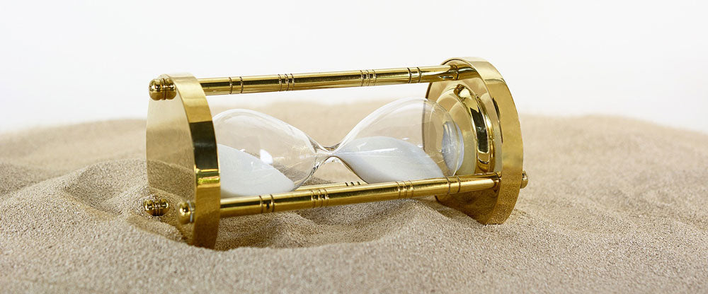 Gold colored hourglass resting on its side. 