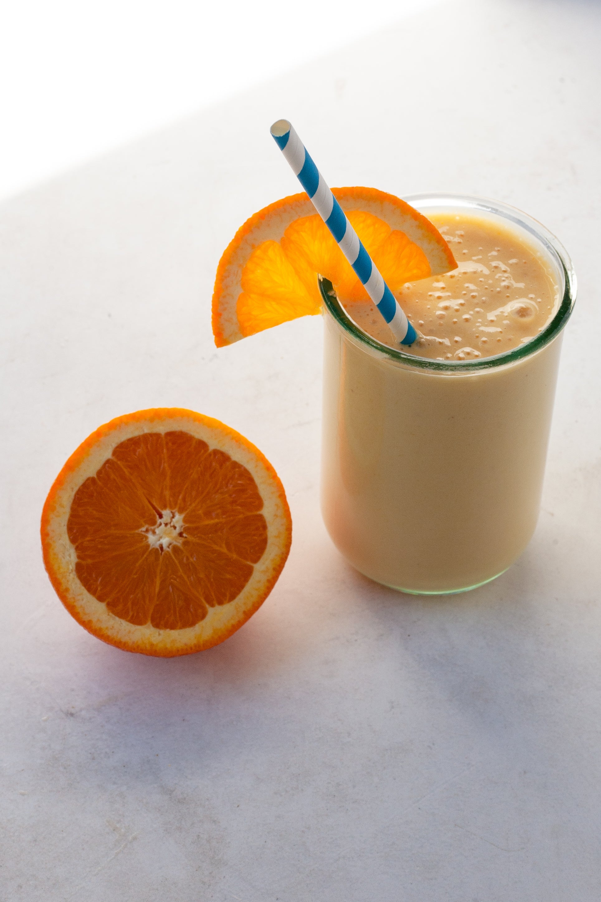 orange creamsicle smoothie next to a half an orange