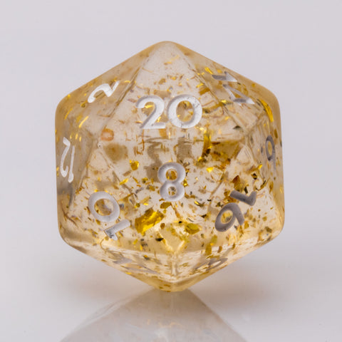 Clear resin D20 with gold flake inclusions on a white background.