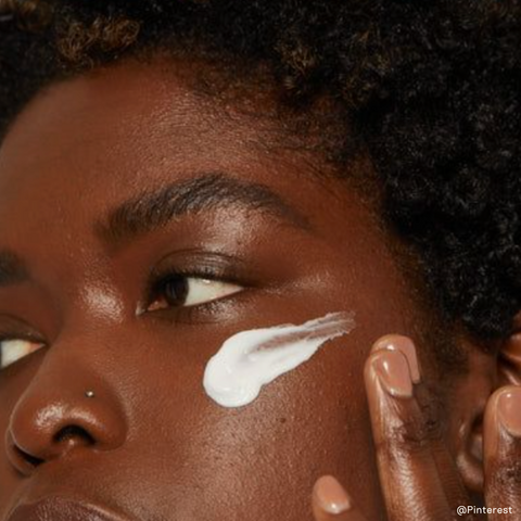 black woman putting on a face moisturizer